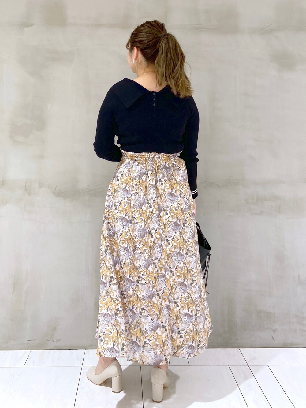 ブラック系のニット/セーター、ホワイト系のスカート、ブラック系のショルダーバッグを着用したレディースの春コーディネートの2枚目の写真