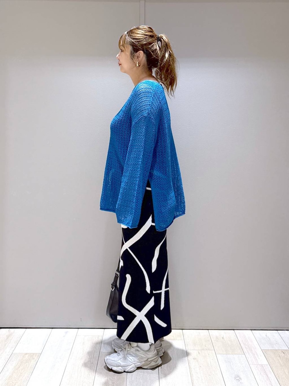 ブラック系のスカート、ブルー系のニット/セーター、ブラック系のショルダーバッグを着用したレディースの秋コーディネートの4枚目の写真