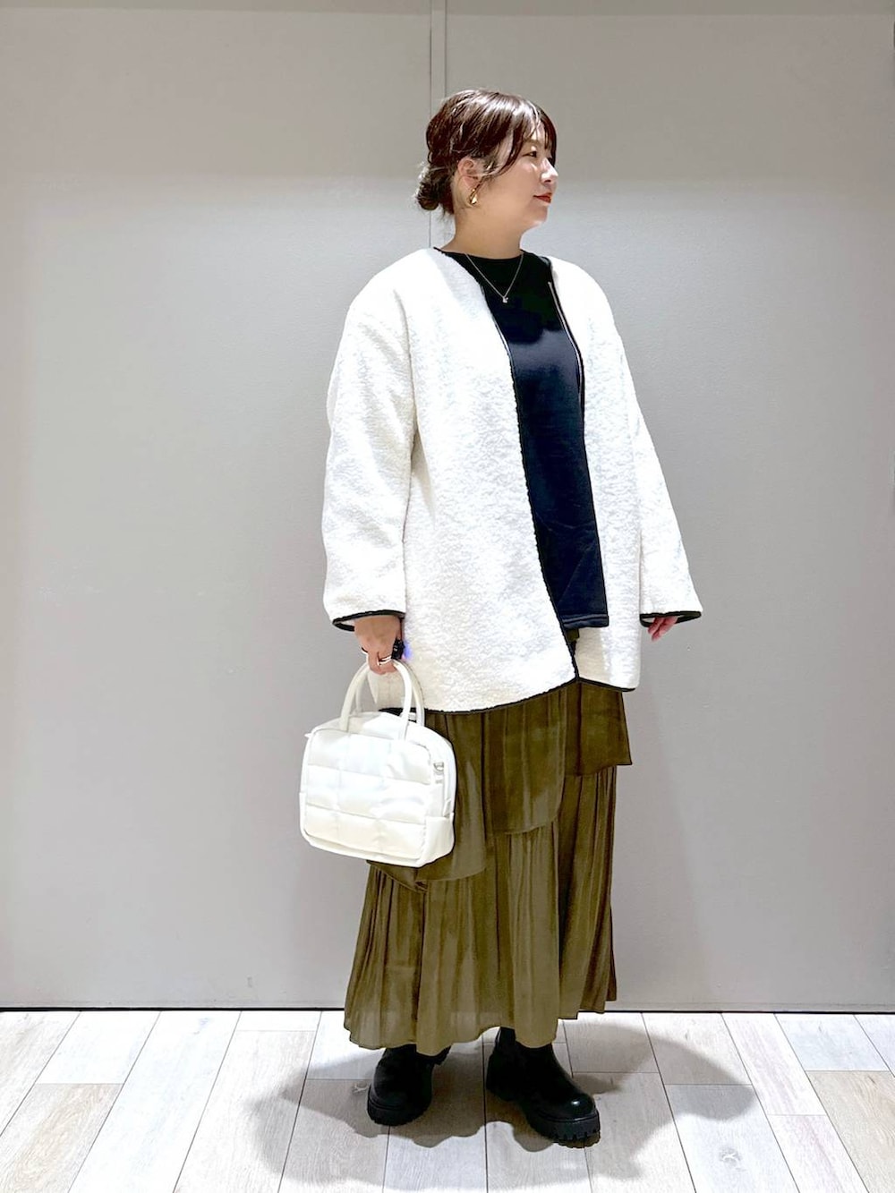 ホワイト系のボストンバッグ、ホワイト系のその他アウター、ブラック系のブーツを着用したレディースの秋コーディネートの5枚目の写真