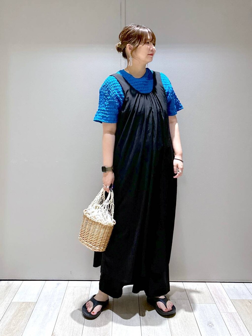 ホワイト系のかごバッグ、ブラック系のサンダル、ブラック系のスラックスを着用したレディースの夏コーディネートの5枚目の写真