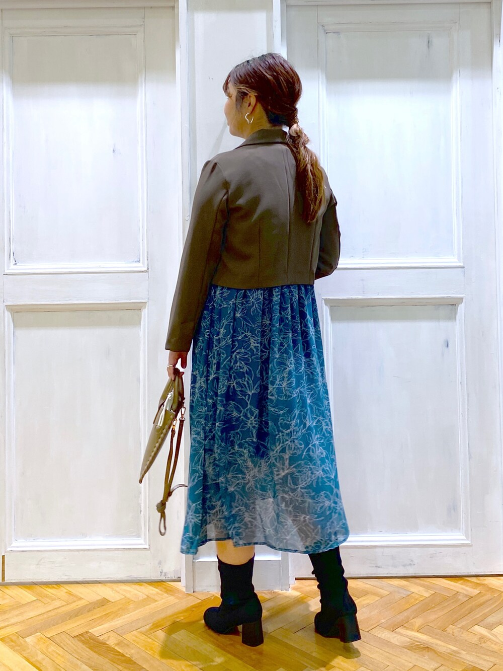 ブラウン系のテーラードジャケット、グリーン系のワンピース、ブラウン系のショルダーバッグを着用したレディースの秋コーディネートの2枚目の写真