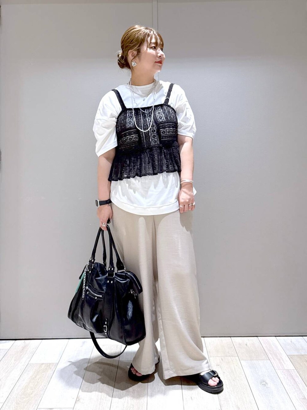 ブラック系のトートバッグ、ホワイト系のTシャツ/カットソー、ブラック系のサンダルを着用したレディースの春コーディネートの5枚目の写真