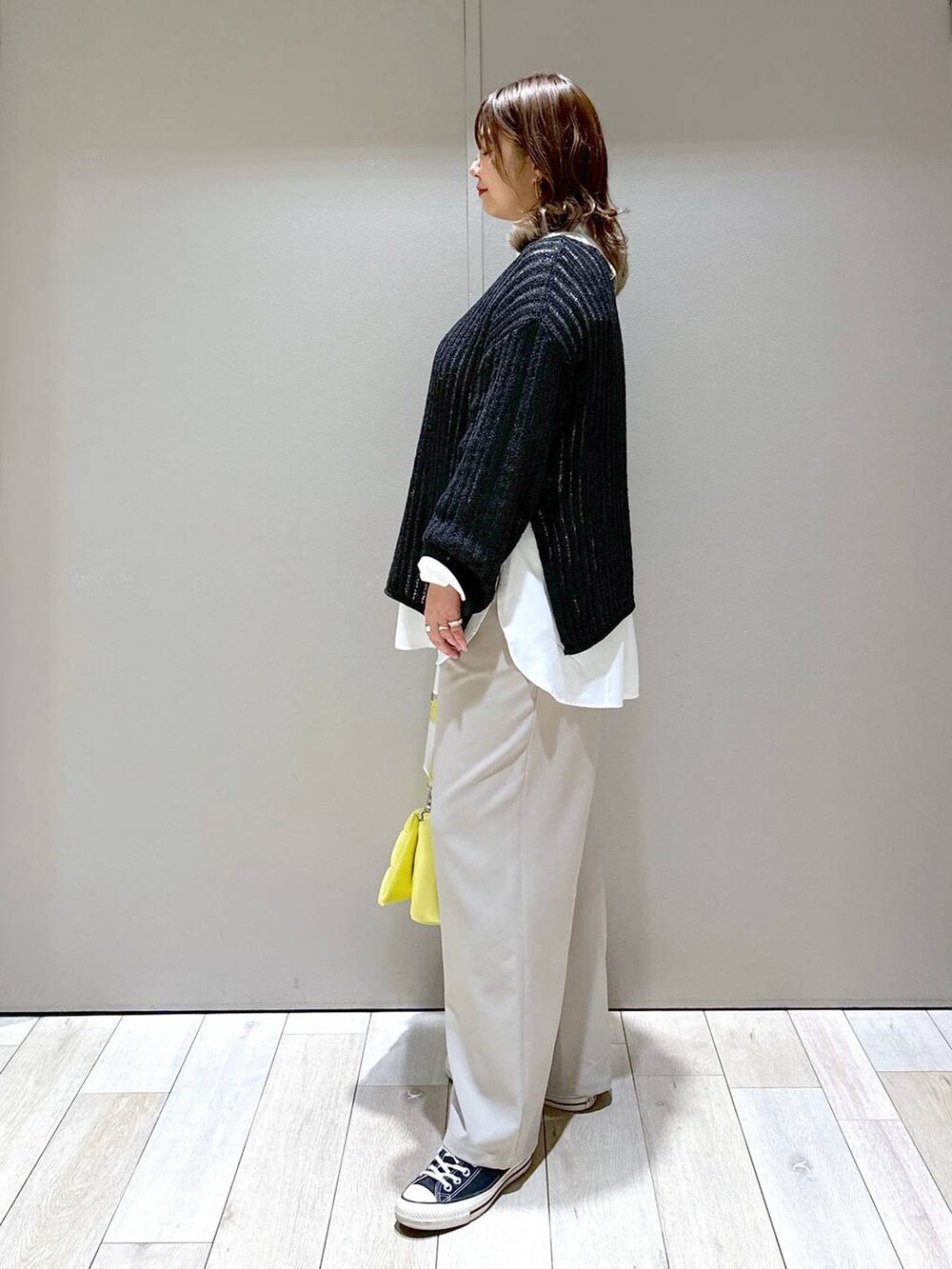 イエロー系のショルダーバッグ、ブラック系のTシャツ/カットソー、ベージュ系のスラックスを着用したレディースの春コーディネートの4枚目の写真