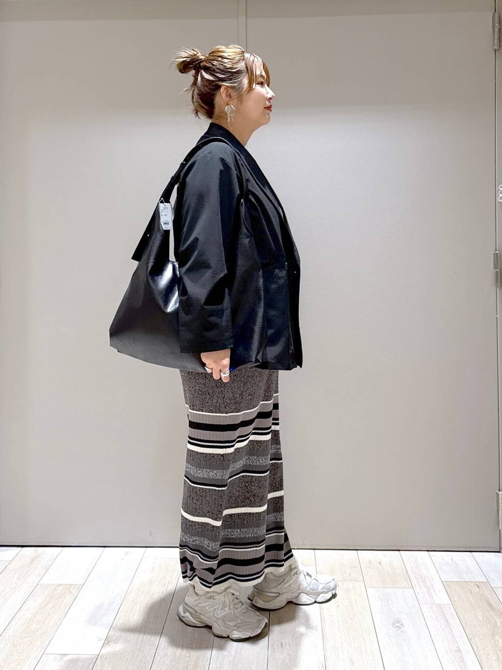 ブラック系のテーラードジャケット、ブラック系のスカート、ブラック系のトートバッグを着用したレディースの春コーディネートの2枚目の写真