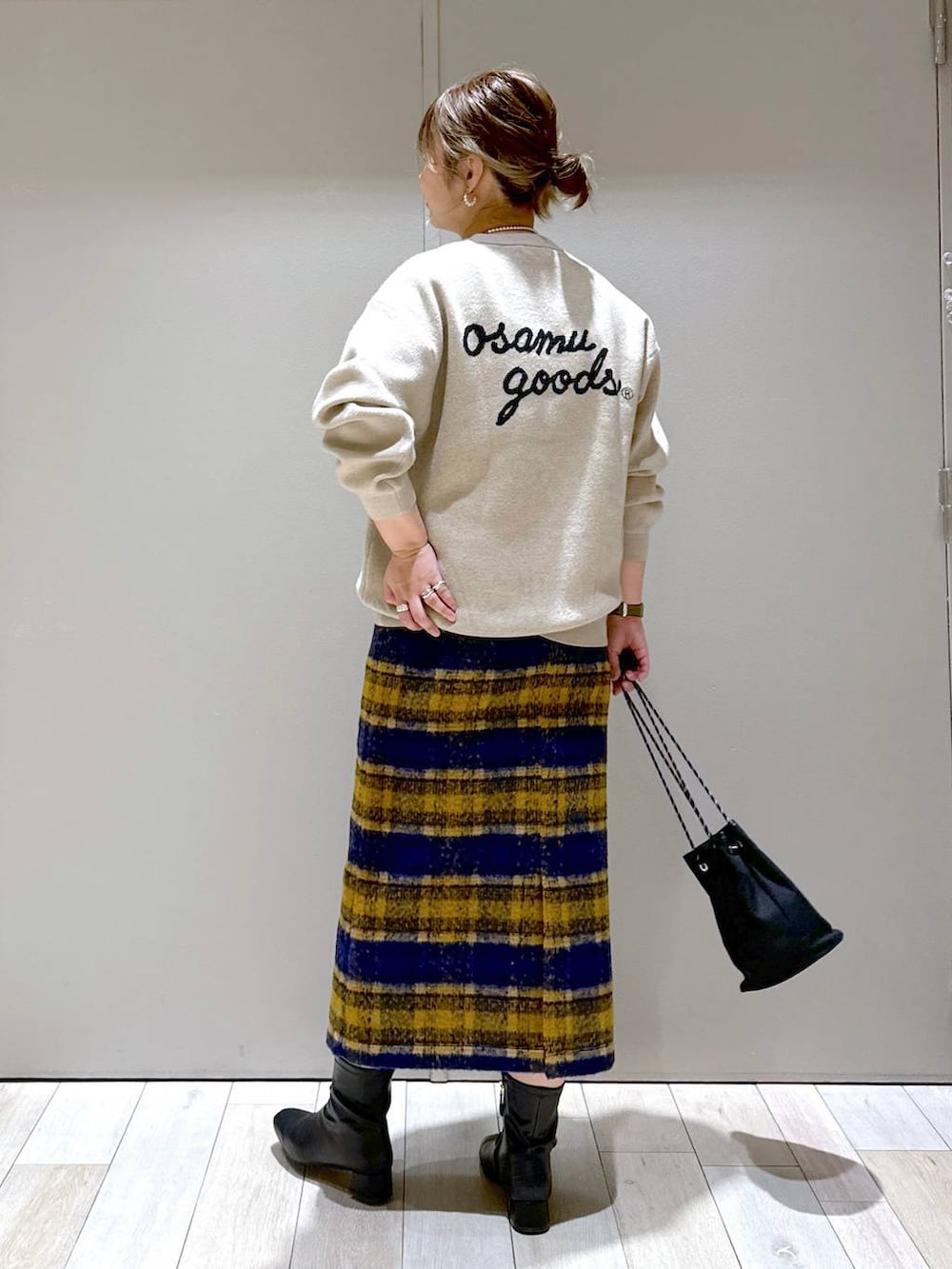 ブラック系のブーツ、ベージュ系のニット/セーター、ゴールド系のピアス（両耳用）を着用したレディースの秋コーディネートの3枚目の写真