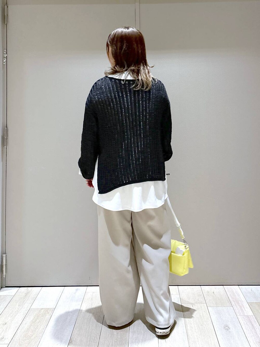 イエロー系のショルダーバッグ、ブラック系のTシャツ/カットソー、ベージュ系のスラックスを着用したレディースの春コーディネートの3枚目の写真