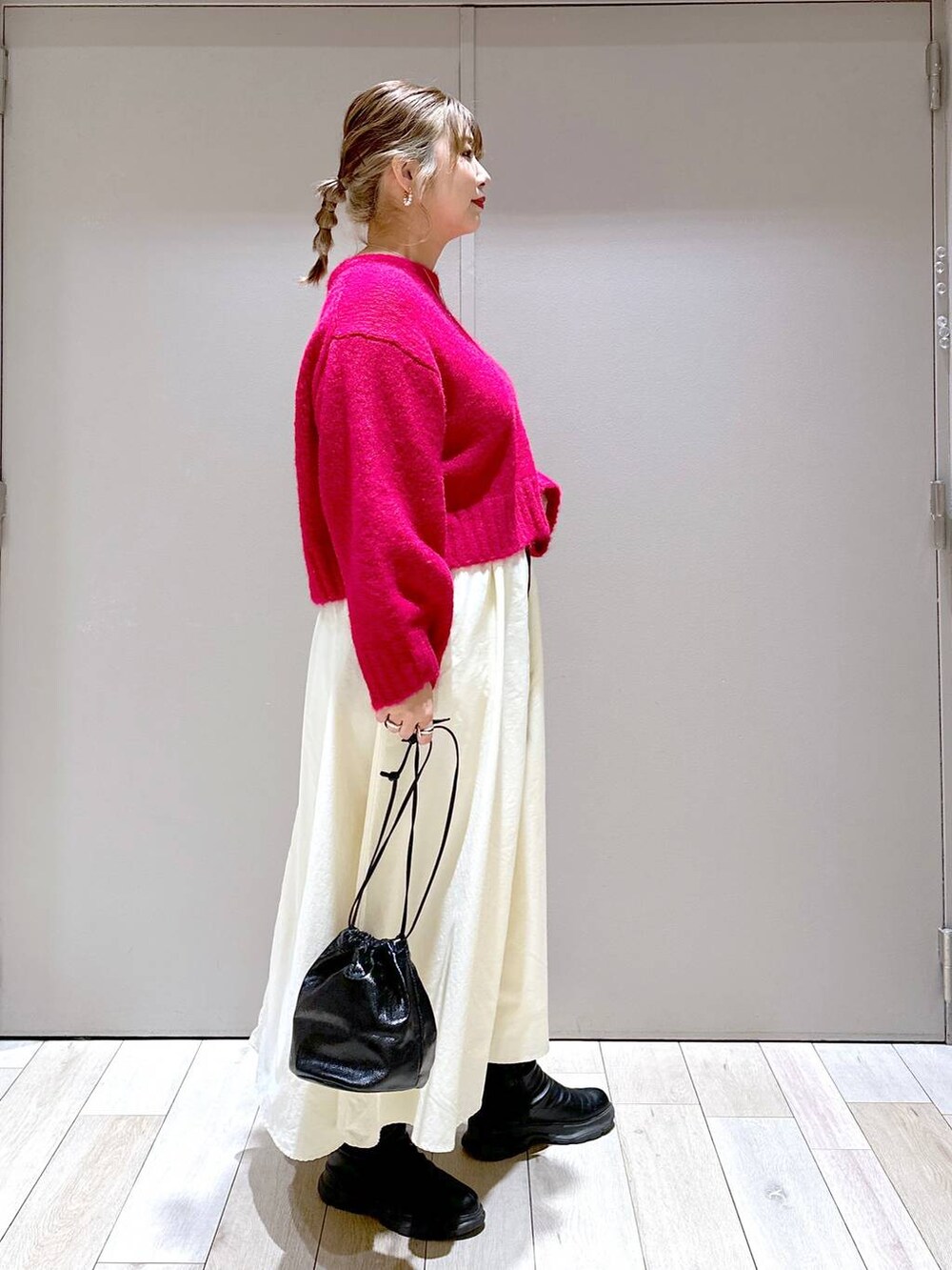 ブラック系のショルダーバッグ、ブラック系のブーツ、ホワイト系のスカートを着用したレディースの冬コーディネートの2枚目の写真