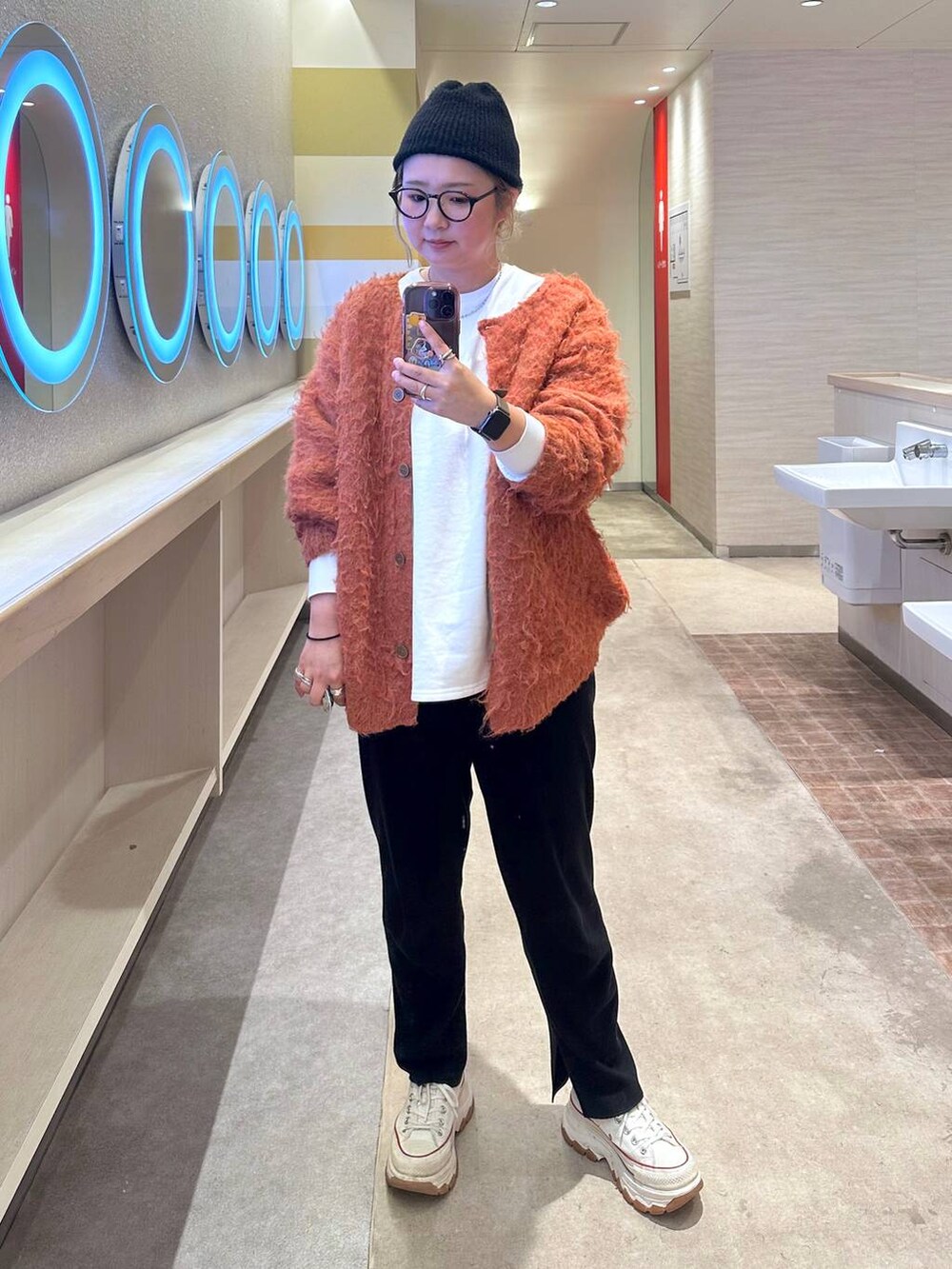 ブラック系のその他パンツ、オレンジ系のカーディガン/ボレロを着用したレディースの冬コーディネートの2枚目の写真