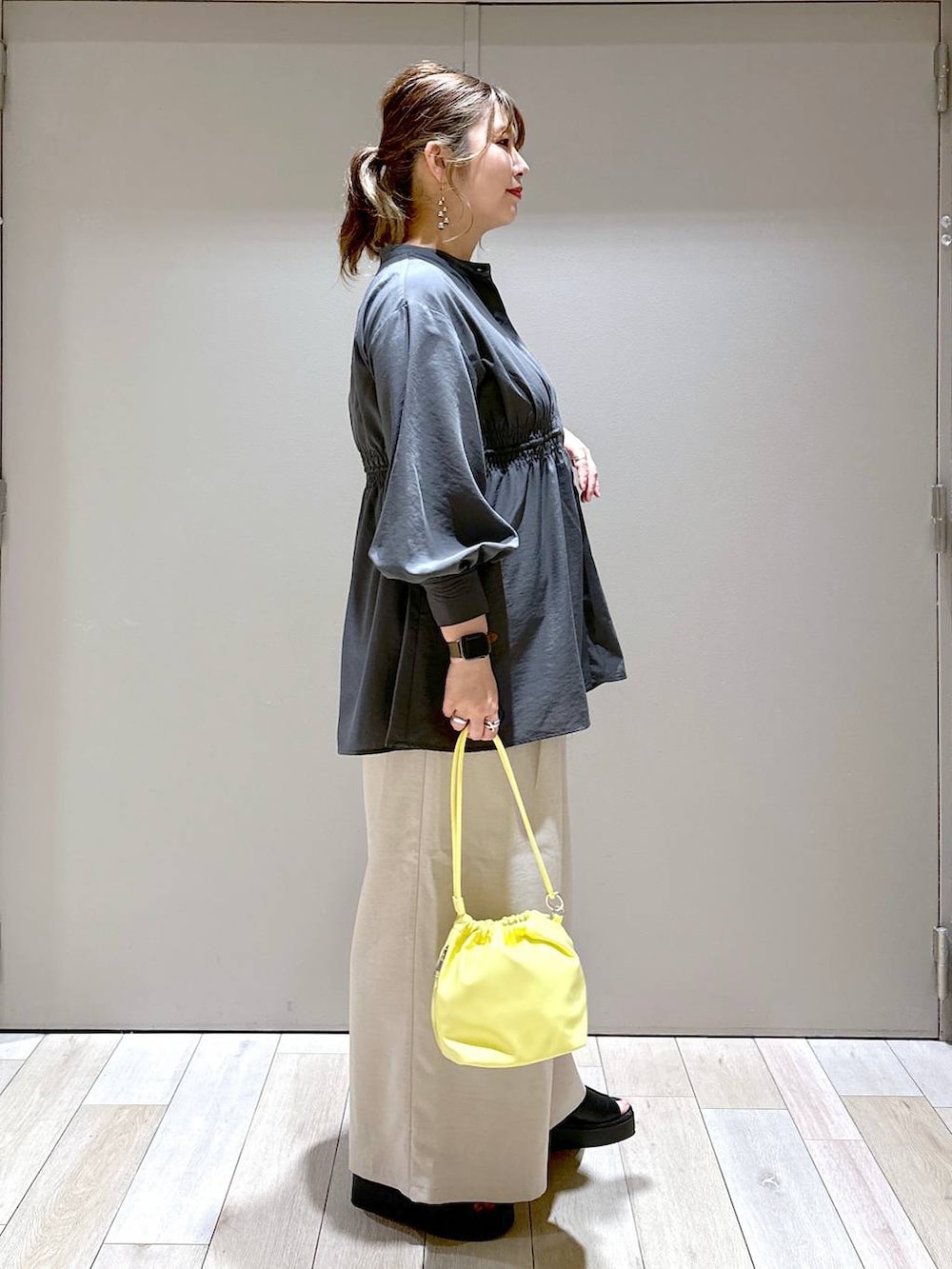 グレー系のシャツ/ブラウス、イエロー系のショルダーバッグ、ブラック系のサンダルを着用したレディースの春コーディネートの2枚目の写真