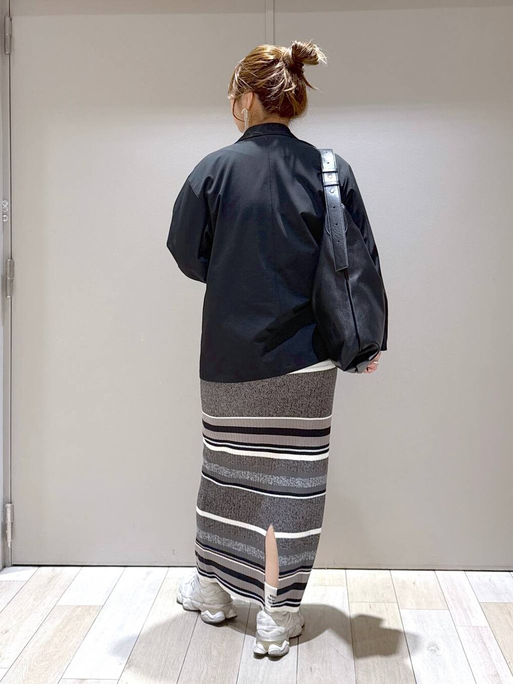 ブラック系のテーラードジャケット、ブラック系のスカート、ブラック系のトートバッグを着用したレディースの春コーディネートの3枚目の写真