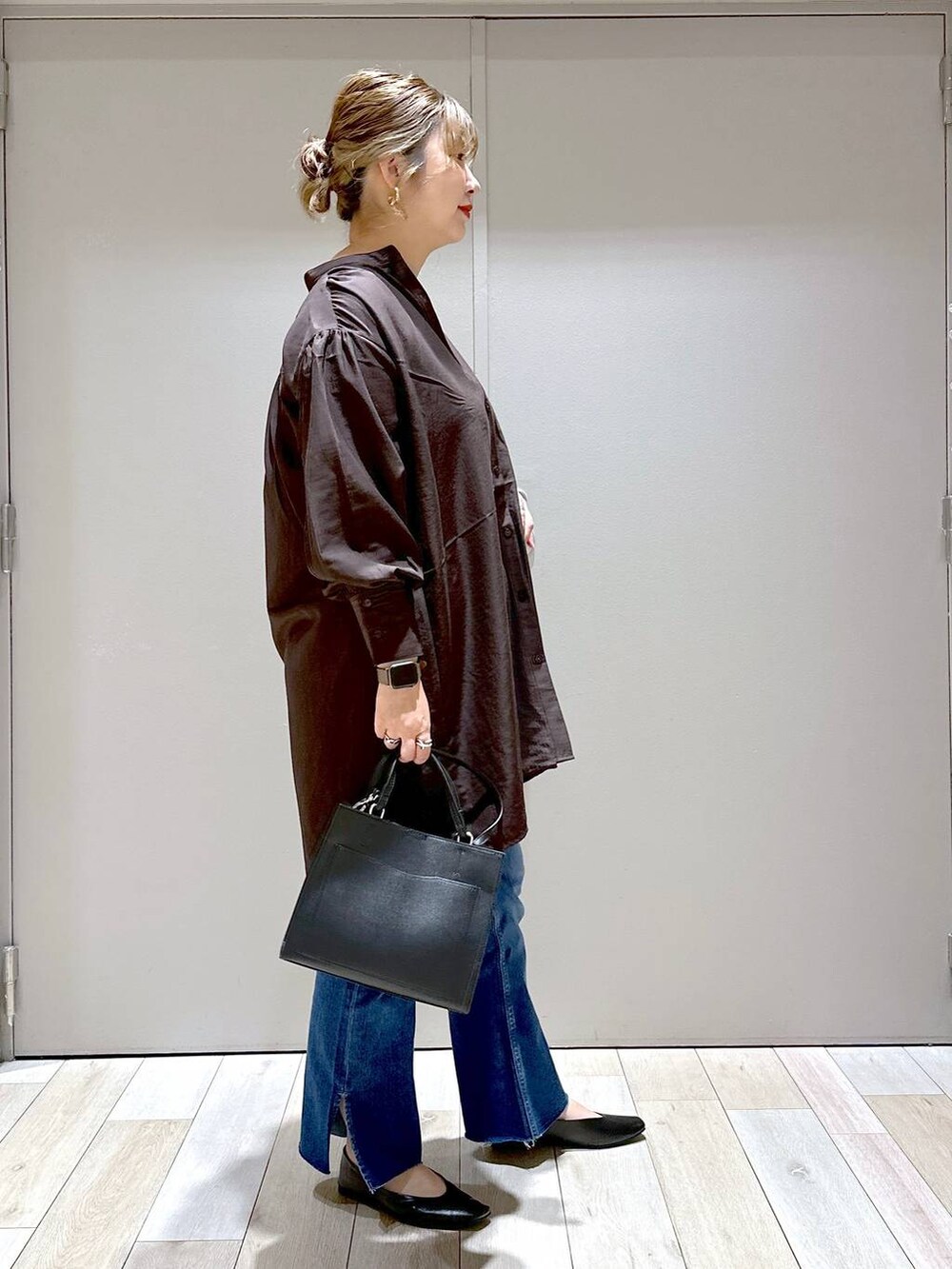 ブラック系のパンプス、ブラウン系のチュニック、ブラック系のショルダーバッグを着用したレディースの秋コーディネートの2枚目の写真