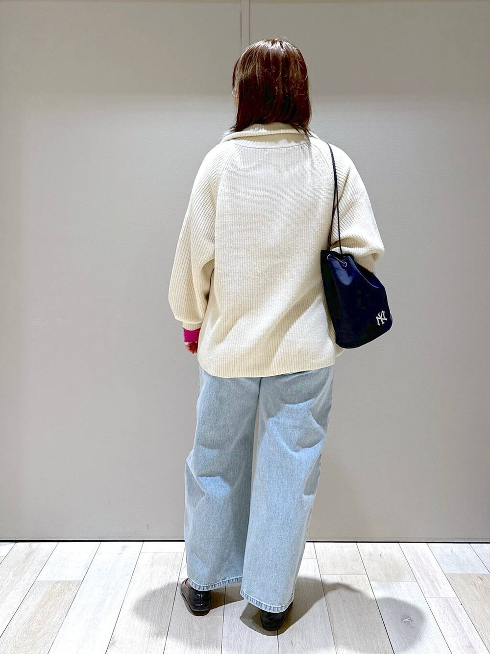 ホワイト系のニット/セーター、ブルー系のデニムパンツ、ブルー系のショルダーバッグを着用したレディースの冬コーディネートの3枚目の写真