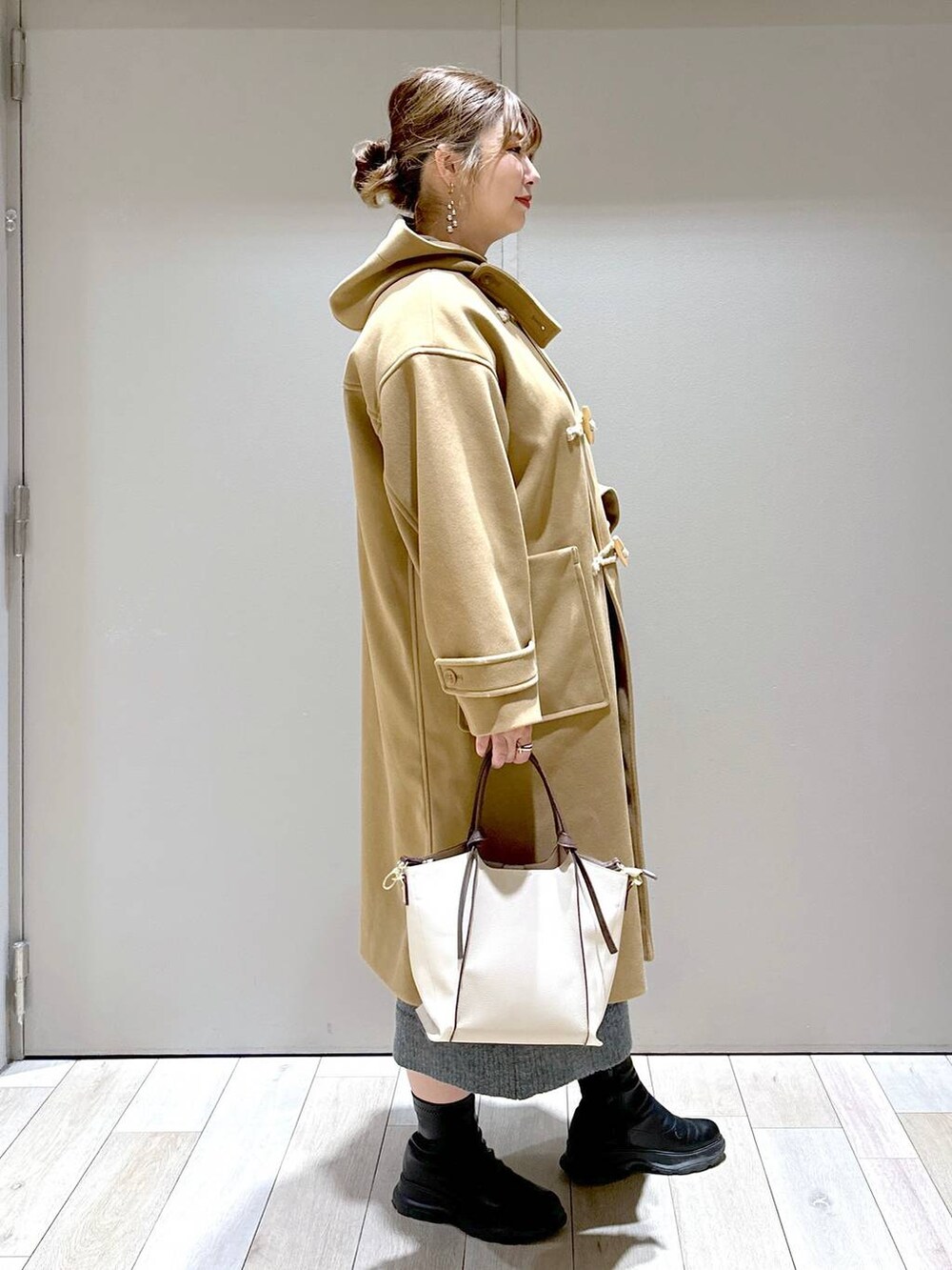 ベージュ系のショルダーバッグ、ブラウン系のダッフルコート、ブラック系のブーツを着用したレディースの冬コーディネートの2枚目の写真