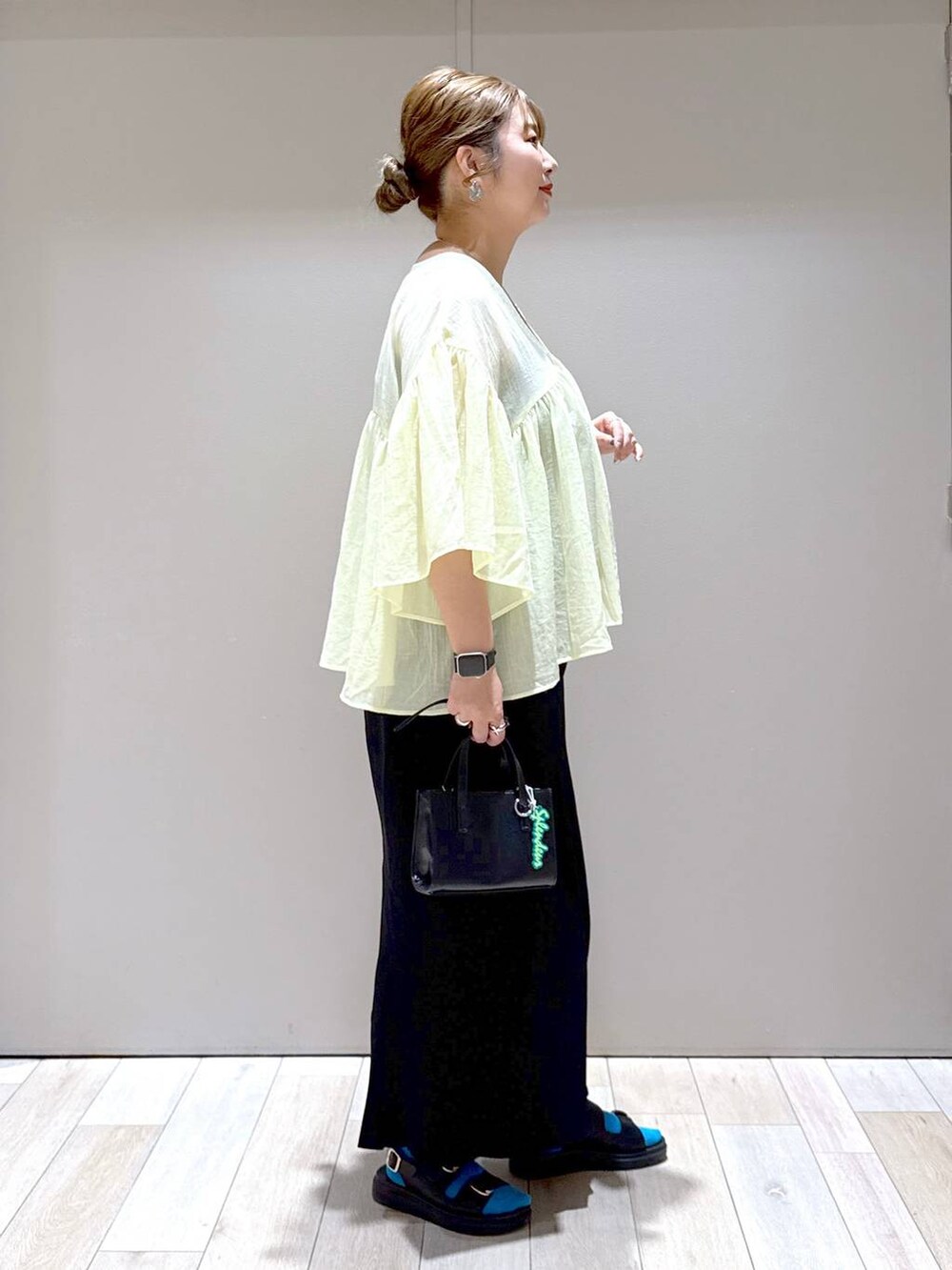 ブラック系のスカート、イエロー系のシャツ/ブラウス、ブラック系のサンダルを着用したレディースの夏コーディネートの2枚目の写真