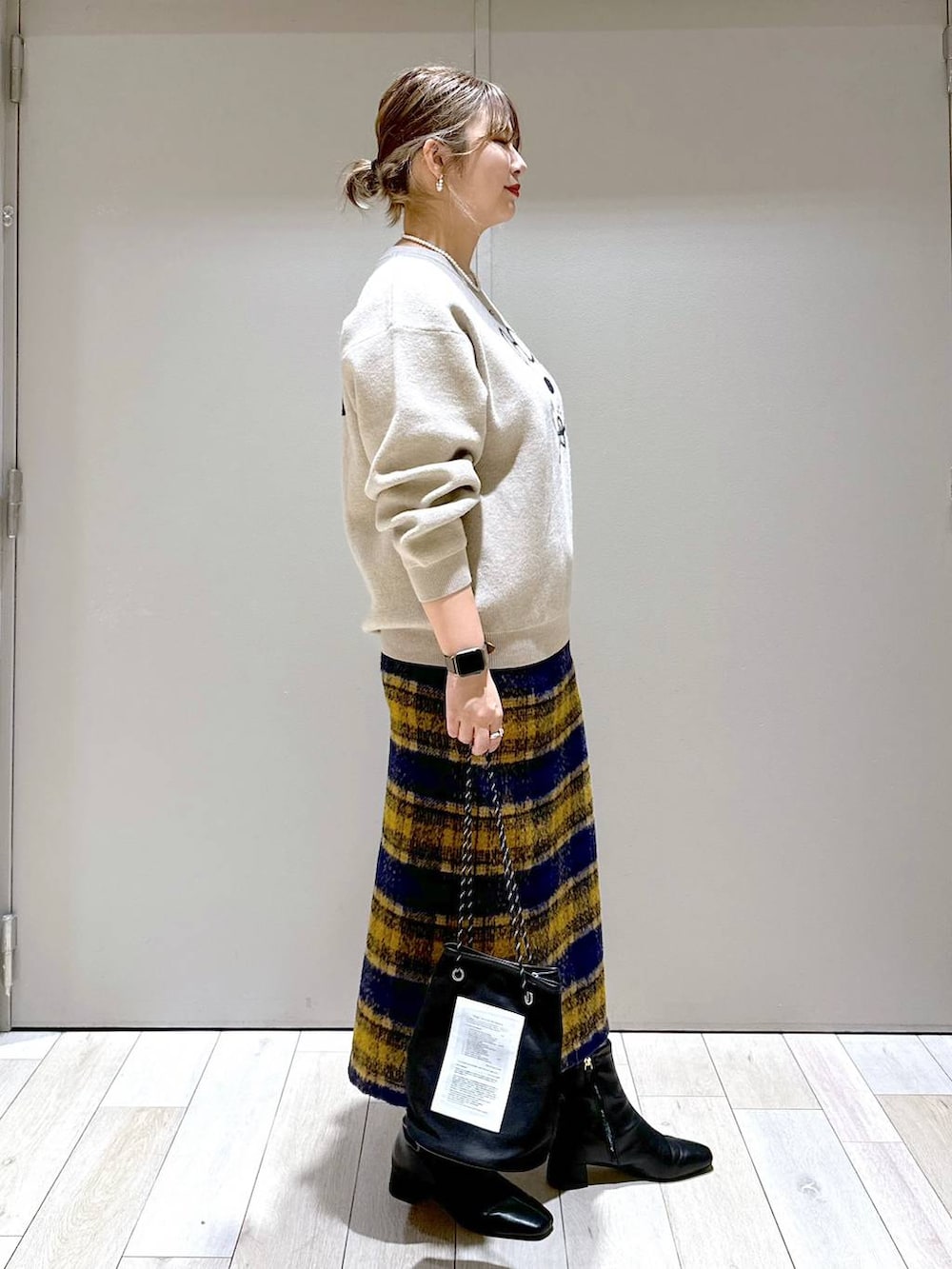 ブラック系のブーツ、ベージュ系のニット/セーター、ゴールド系のピアス（両耳用）を着用したレディースの秋コーディネートの2枚目の写真