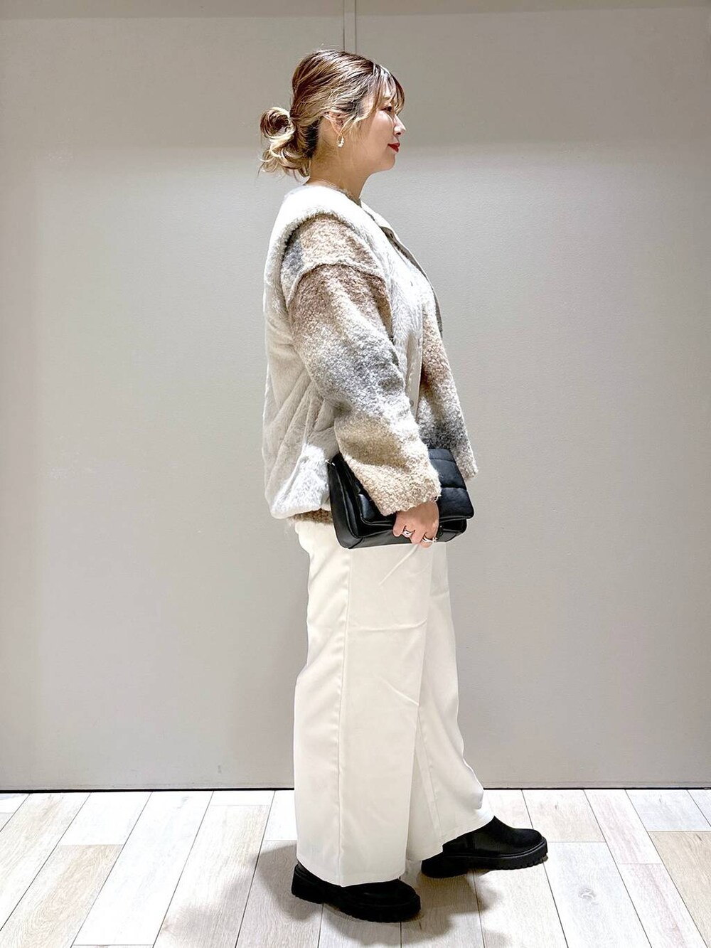 ホワイト系のモッズコート、ブラック系のブーツ、ブラック系のショルダーバッグを着用したレディースの秋コーディネートの2枚目の写真