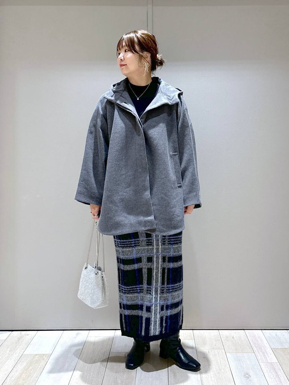 シルバー系のショルダーバッグ、グレー系のポンチョ、ブラック系のニット/セーターを着用したレディースの秋コーディネートの5枚目の写真
