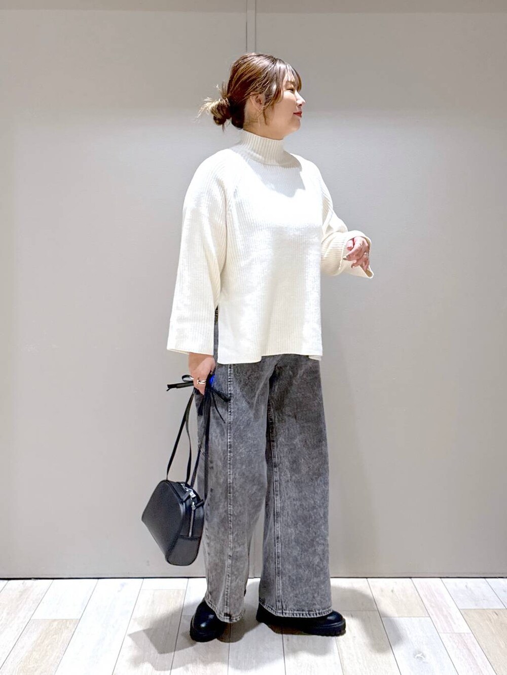 ブラック系のブーツ、ホワイト系のニット/セーター、グレー系のデニムパンツを着用したレディースの冬コーディネートの2枚目の写真