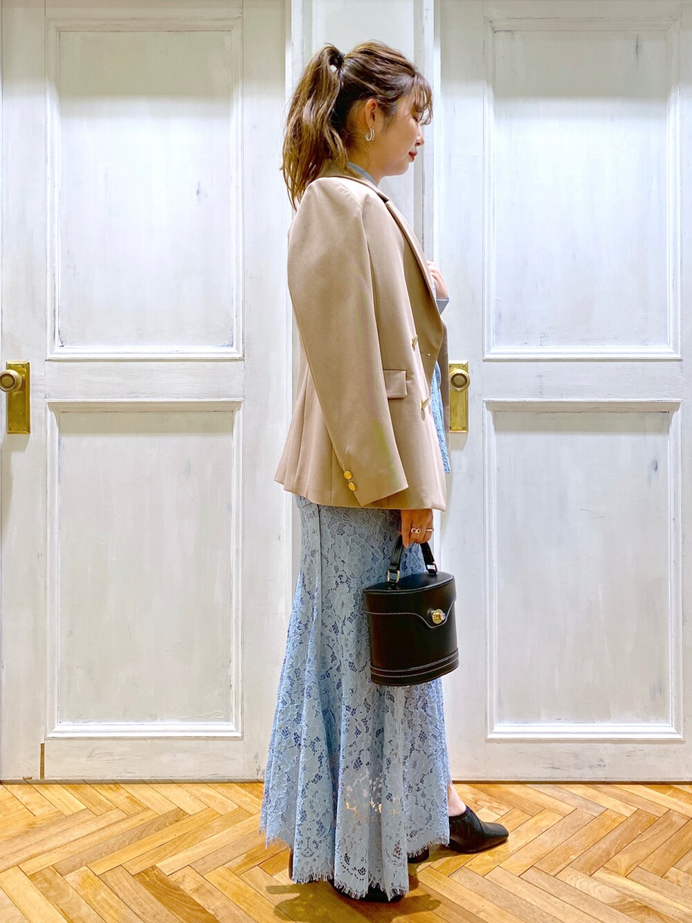 ブラック系のパンプス、ブラック系のショルダーバッグ、ブルー系のシャツ/ブラウスを着用したレディースの春コーディネートの3枚目の写真