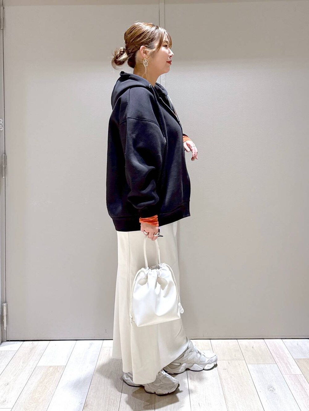 ホワイト系のスカート、ブラック系のパーカー、オレンジ系のTシャツ/カットソーを着用したレディースの冬コーディネートの2枚目の写真