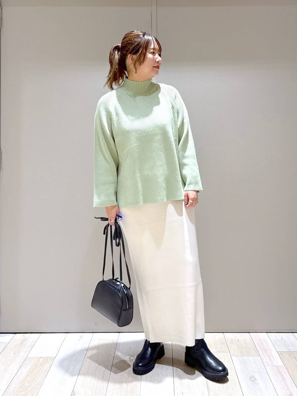 ブラック系のスカート、ブラック系のブーツ、ホワイト系のニット/セーターを着用したレディースの冬コーディネートの5枚目の写真