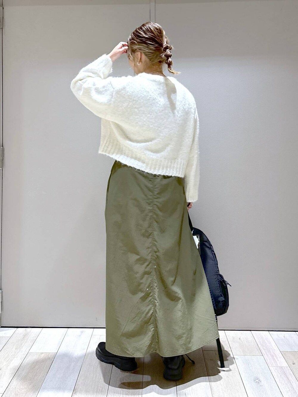 ブラック系のバックパック/リュック、ブラック系のブーツ、グリーン系のスカートを着用したレディースの冬コーディネートの3枚目の写真