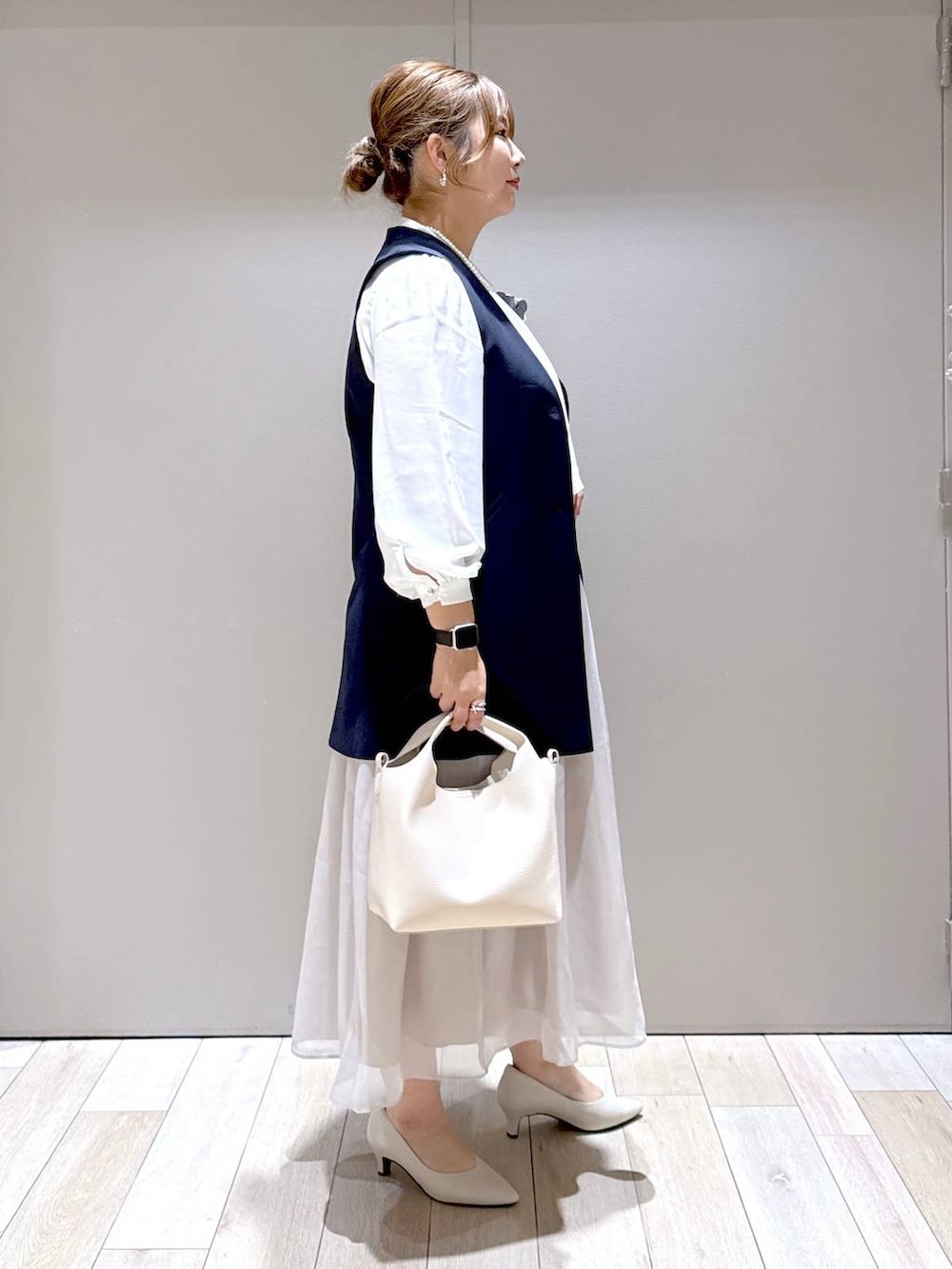 ベージュ系のスカート、ホワイト系のシャツ/ブラウス、ブルー系のスーツベストを着用したレディースの冬コーディネートの2枚目の写真