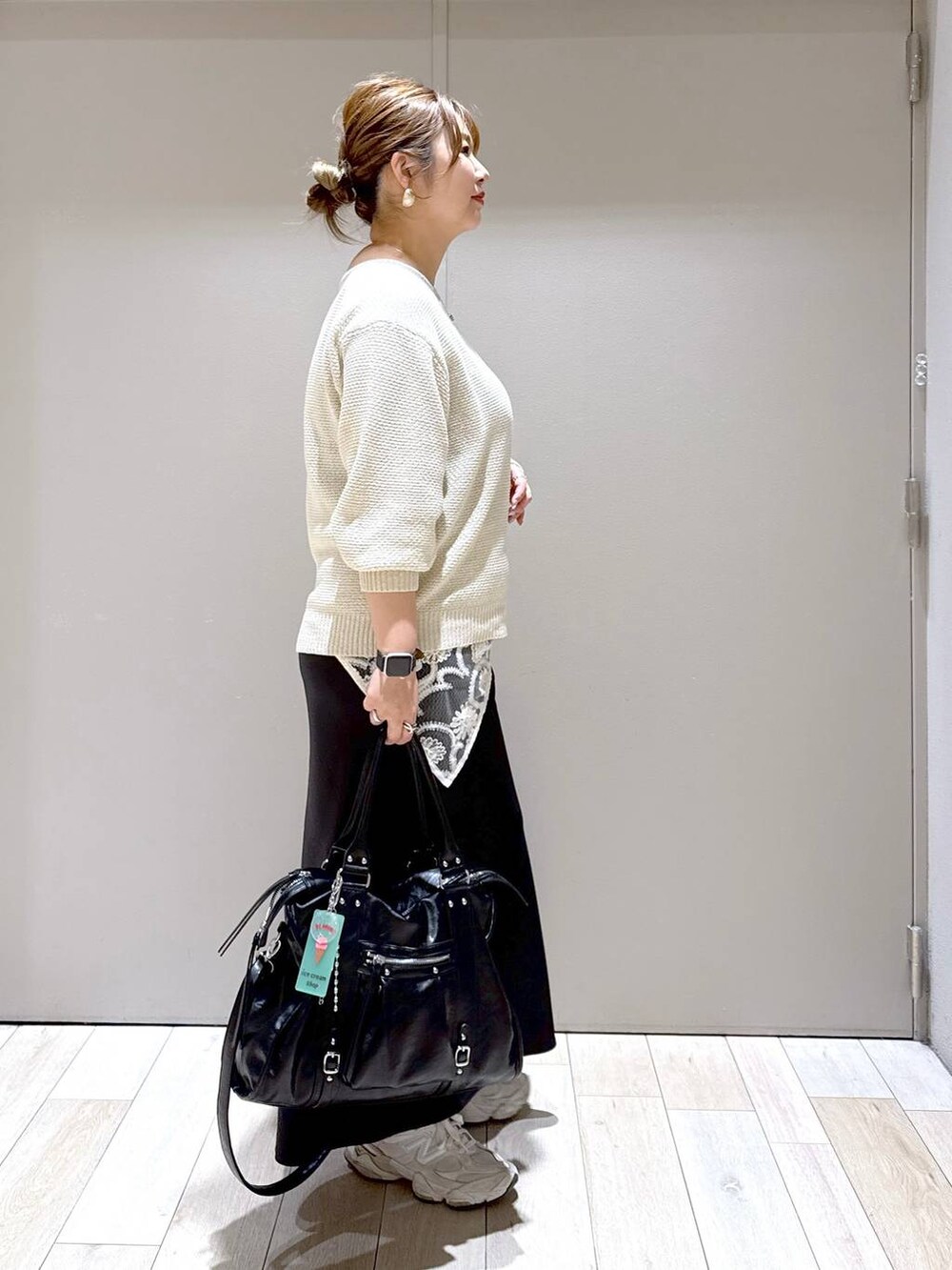 ブラック系のスカート、ブラック系のトートバッグ、ホワイト系のニット/セーターを着用したレディースの春コーディネートの2枚目の写真