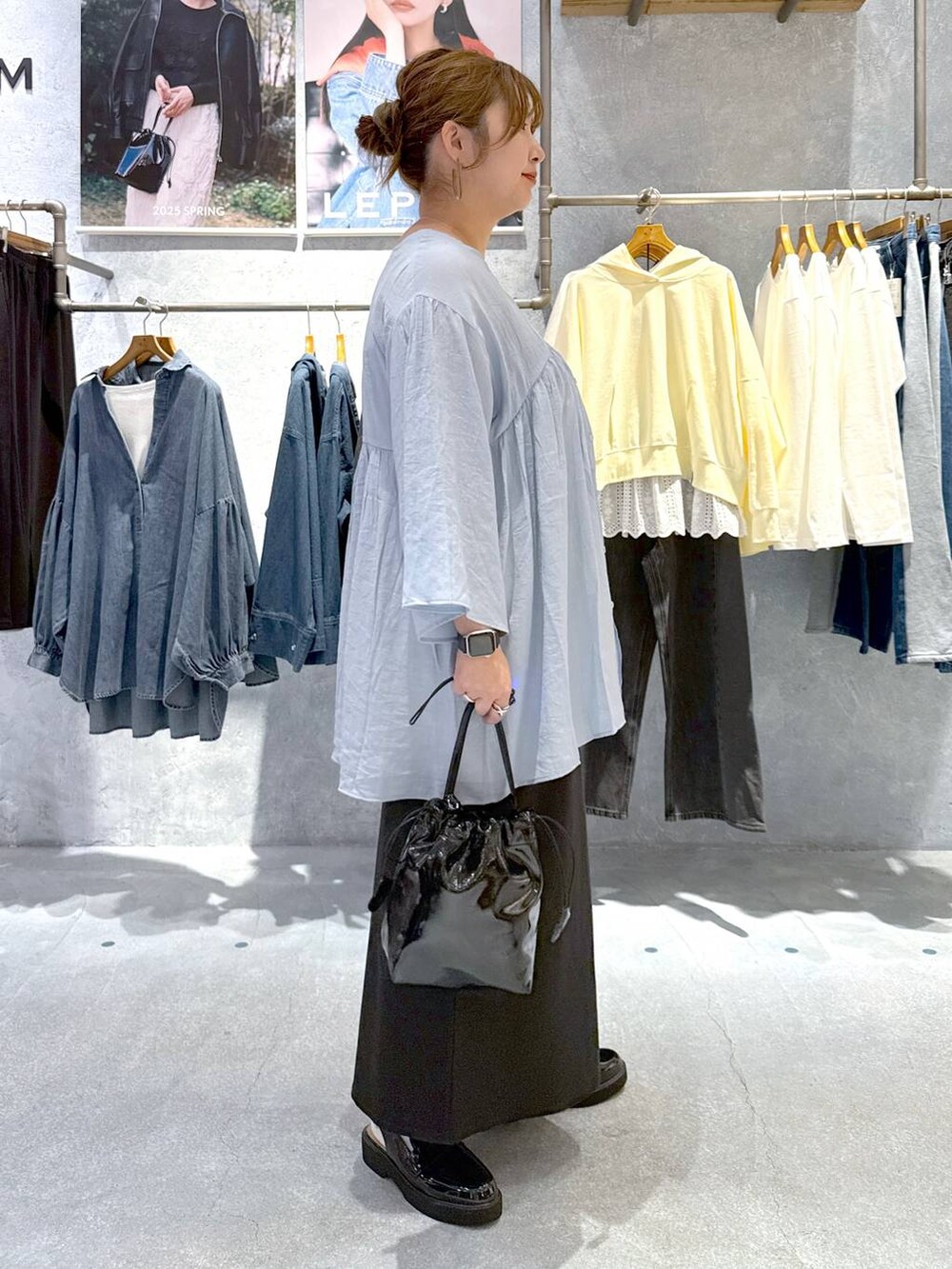 ブラック系のローファー、ブラック系のショルダーバッグ、ブラック系のスカートを着用したレディースの春コーディネートの2枚目の写真