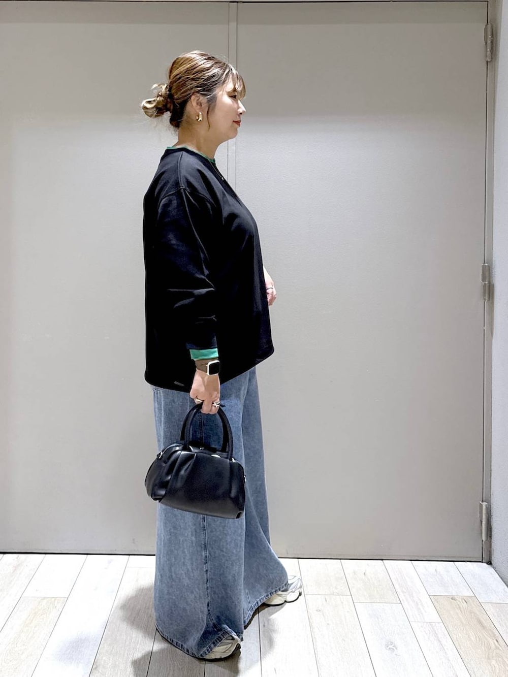 ブラック系のショルダーバッグ、ブラック系のTシャツ/カットソー、ブルー系のデニムパンツを着用したレディースの秋コーディネートの2枚目の写真