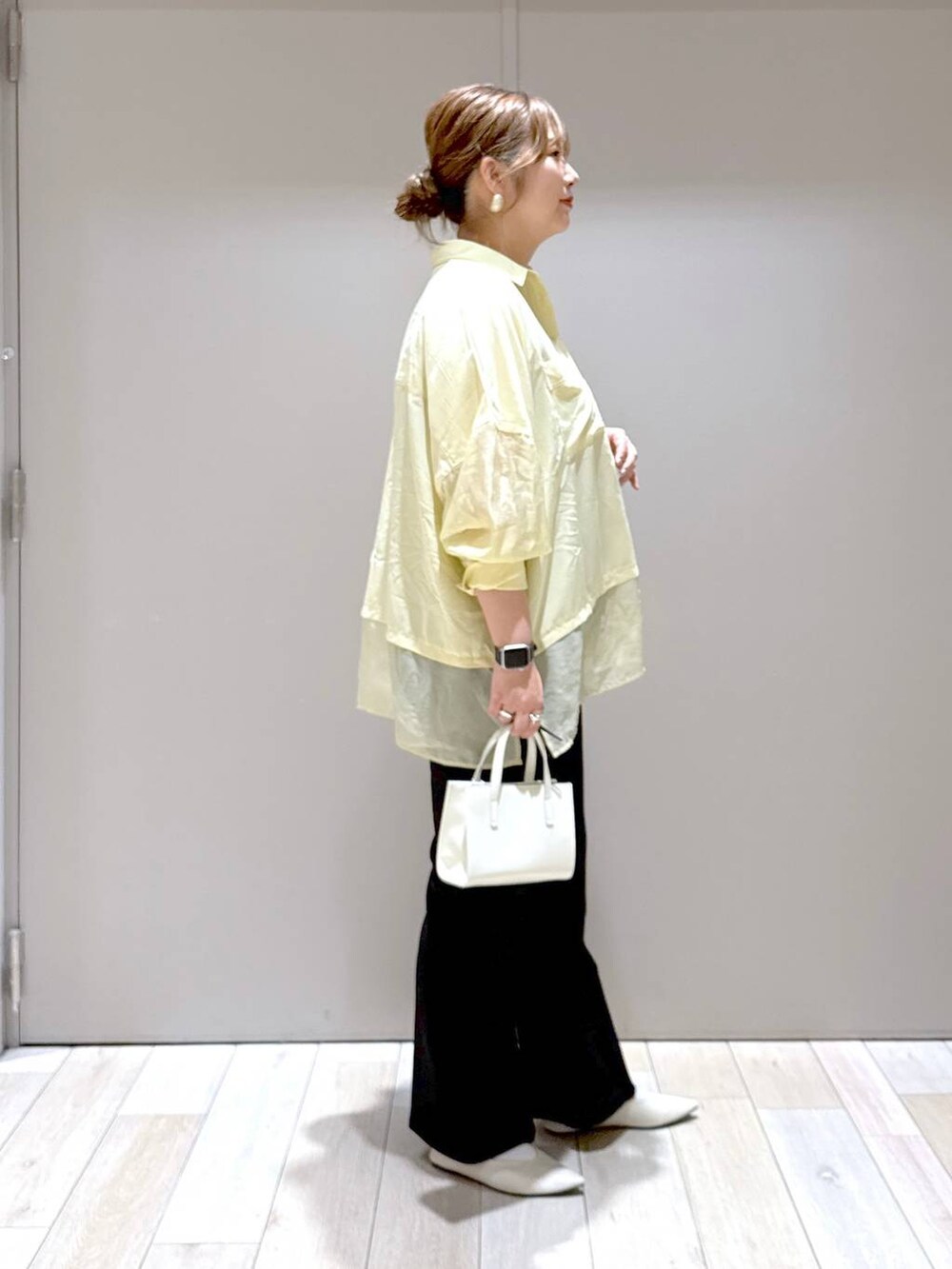 ブラック系のスラックス、ホワイト系のパンプス、イエロー系のシャツ/ブラウスを着用したレディースの春コーディネートの2枚目の写真