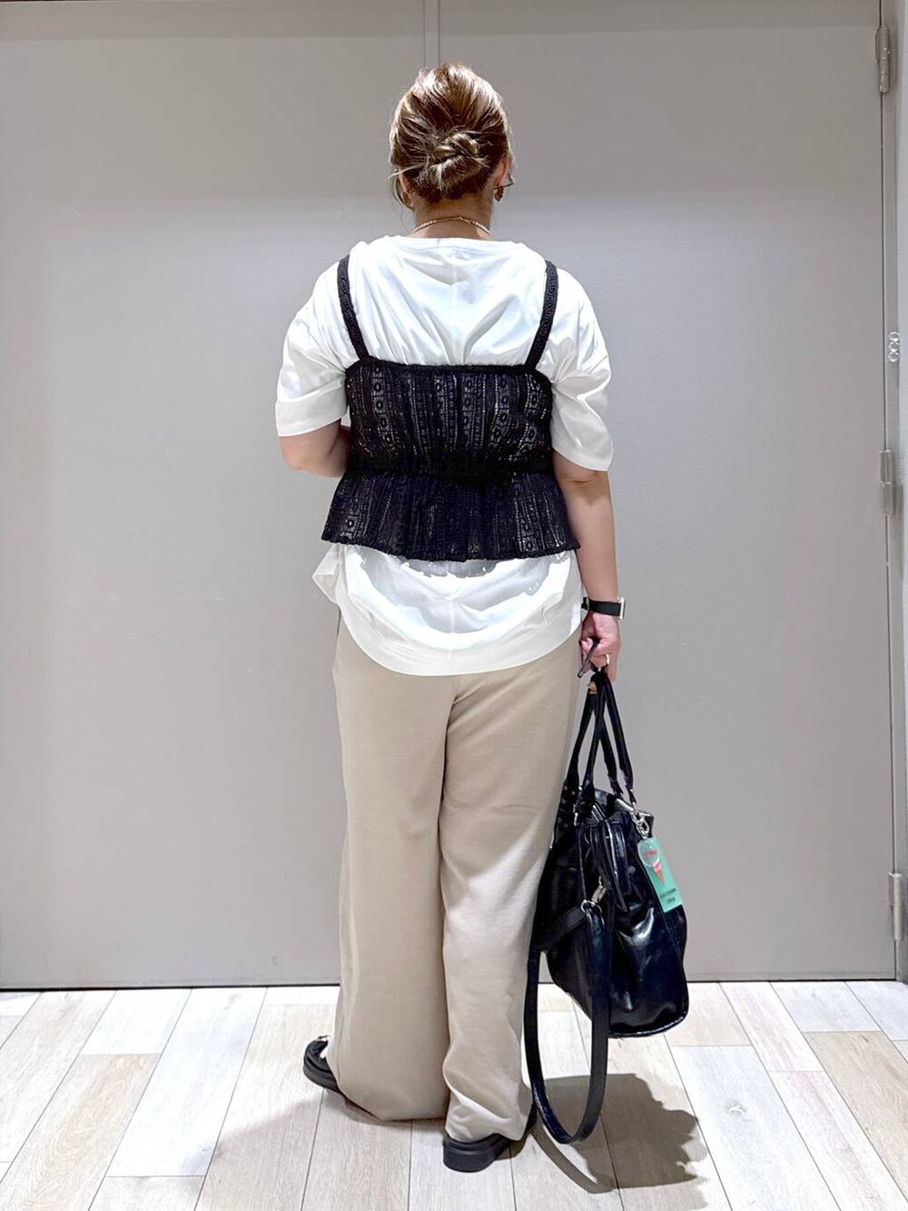 ブラック系のトートバッグ、ホワイト系のTシャツ/カットソー、ブラック系のサンダルを着用したレディースの春コーディネートの3枚目の写真