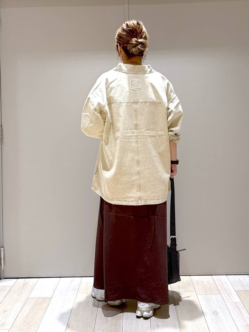 ブラック系のショルダーバッグ、ベージュ系のシャツ/ブラウス、ブラウン系のスカートを着用したレディースの秋コーディネートの3枚目の写真