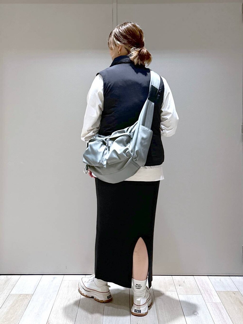 ブラック系のスカート、グリーン系のボディバッグ/ウエストポーチ、ホワイト系のTシャツ/カットソーを着用したレディースの秋コーディネートの3枚目の写真