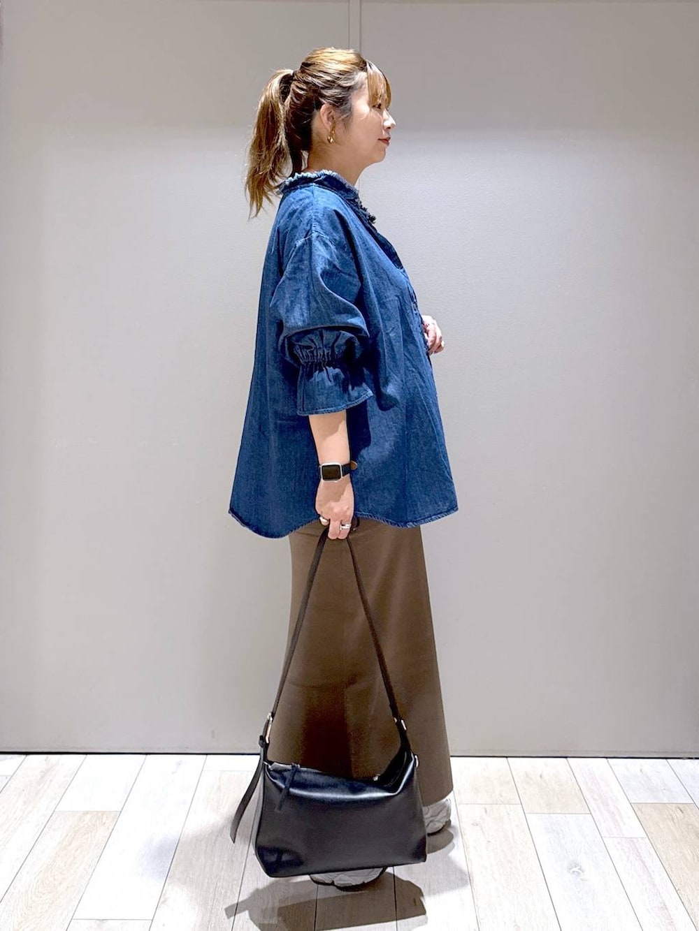 ブラウン系のスカート、ブラック系のショルダーバッグ、ブルー系のシャツ/ブラウスを着用したレディースの夏コーディネートの2枚目の写真