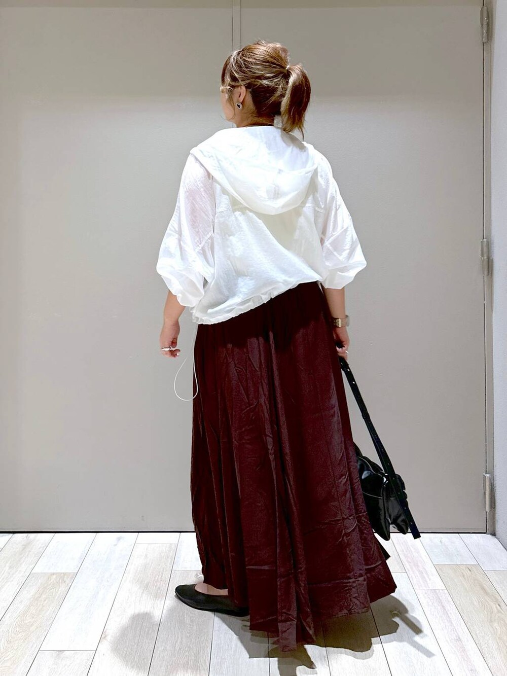 ブラック系のショルダーバッグ、ブラック系のパンプス、ブラウン系のスカートを着用したレディースの秋コーディネートの3枚目の写真