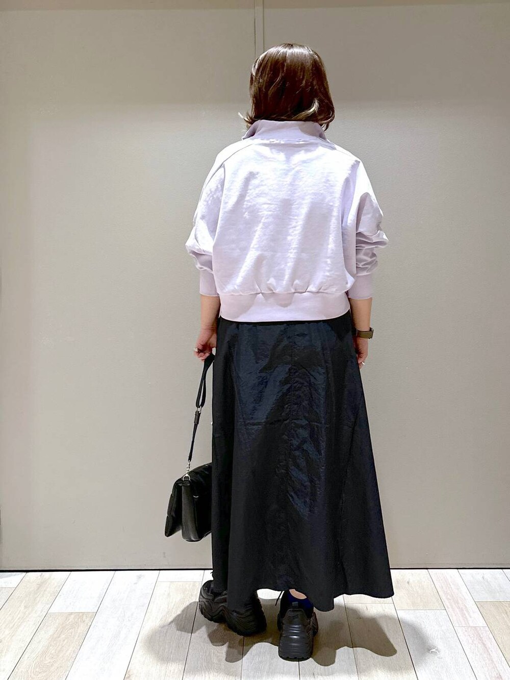 ブラック系のスニーカー、ブラック系のショルダーバッグ、ブラック系のスカートを着用したレディースの春コーディネートの3枚目の写真