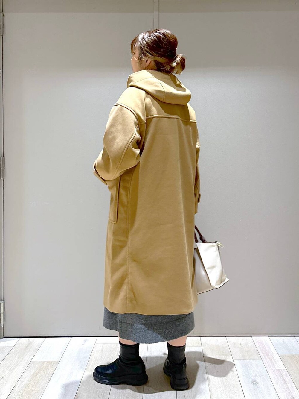 ベージュ系のショルダーバッグ、ブラウン系のダッフルコート、ブラック系のブーツを着用したレディースの冬コーディネートの3枚目の写真