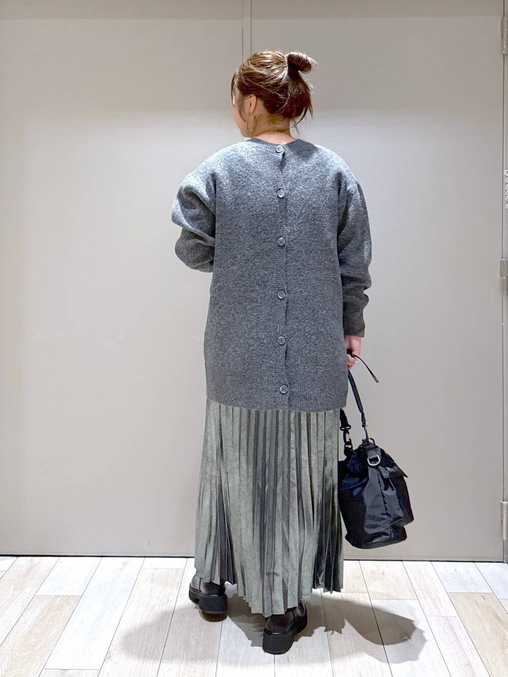 ブラック系のショルダーバッグ、ブラック系のブーツ、グレー系のスカートを着用したレディースの冬コーディネートの3枚目の写真