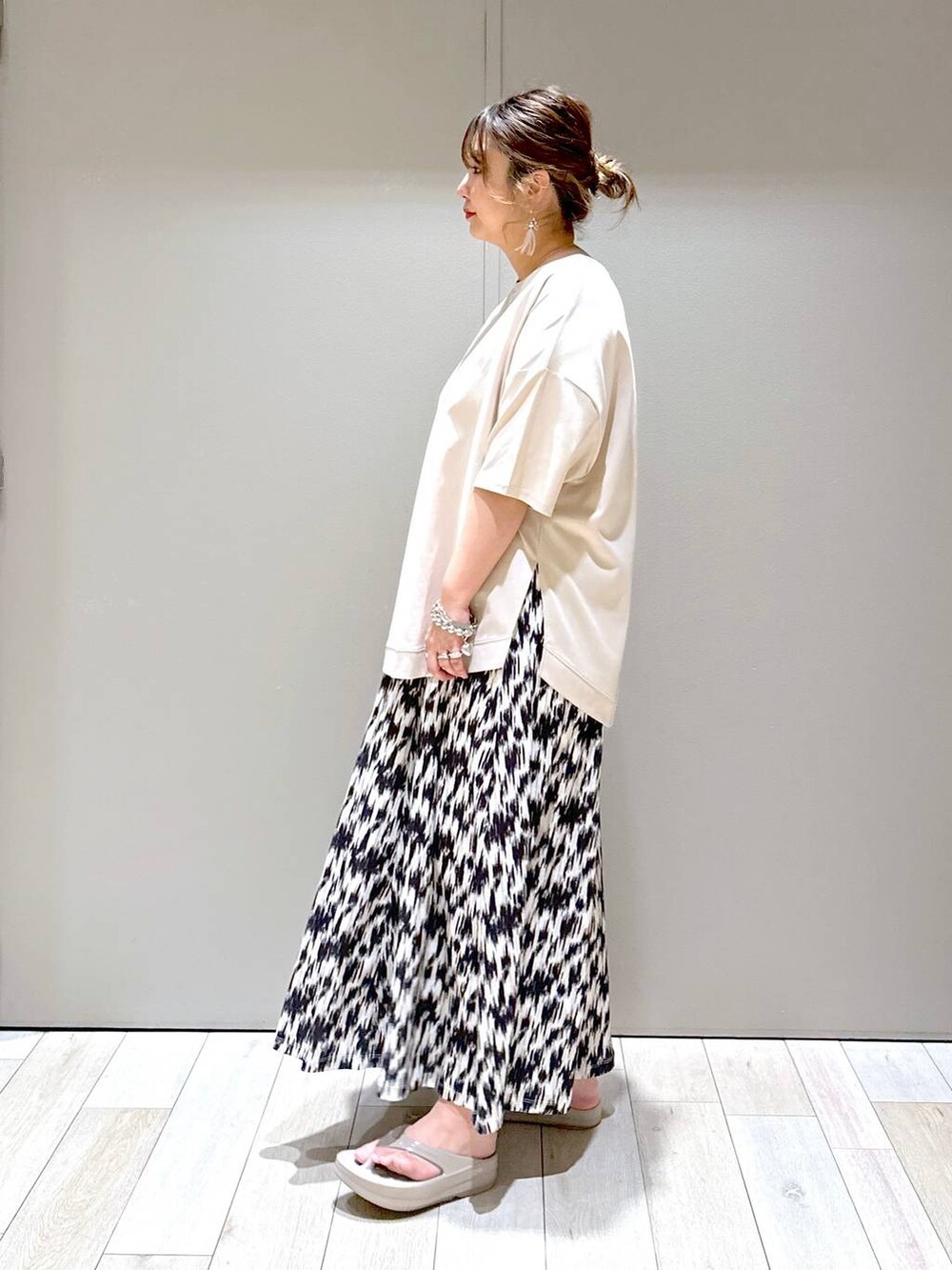 ゴールド系のショルダーバッグ、ブラック系のスカート、ベージュ系のTシャツ/カットソーを着用したレディースの春コーディネートの4枚目の写真