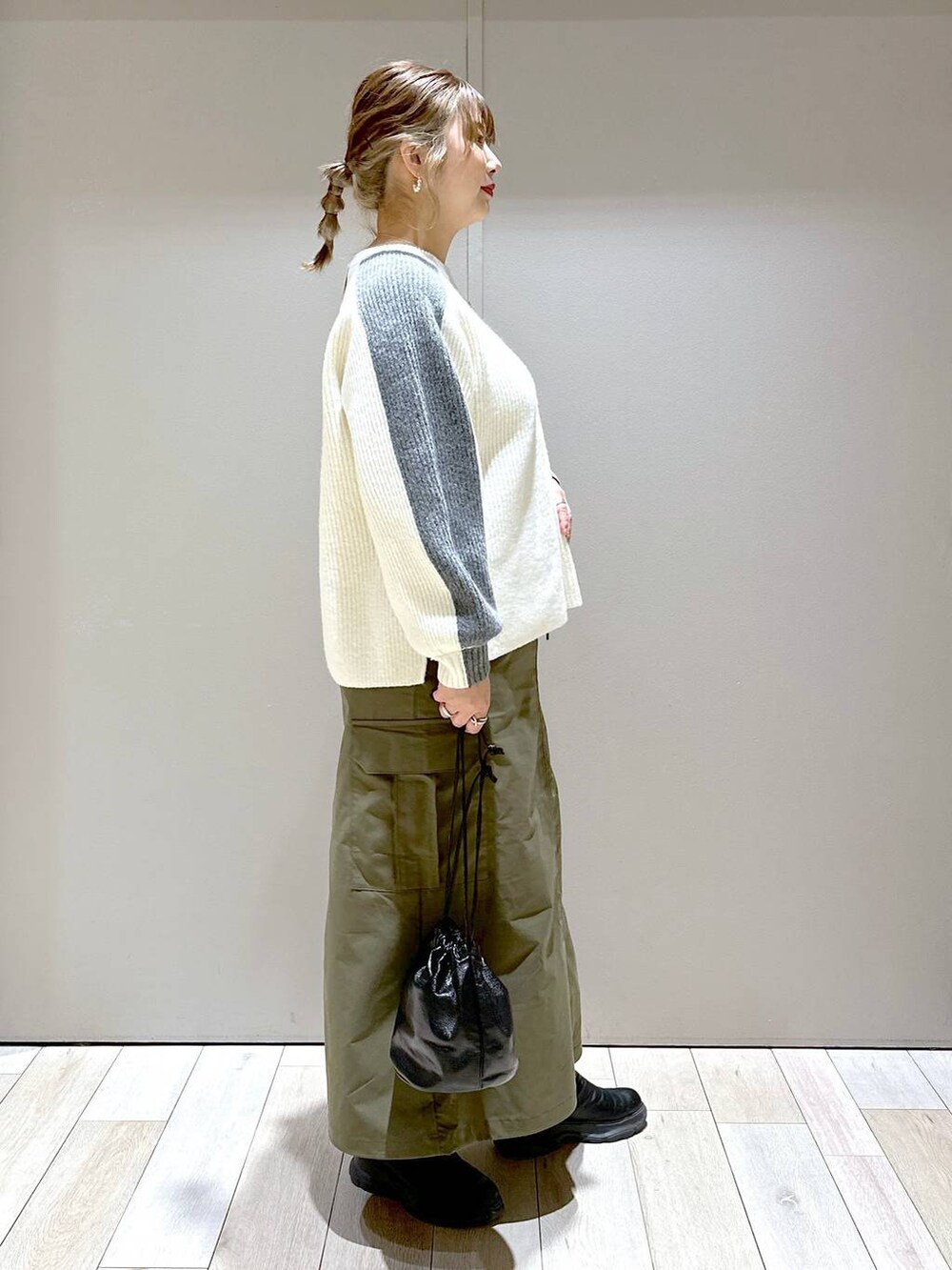 ホワイト系のニット/セーター、グリーン系のスカート、ブラック系のブーツを着用したレディースの冬コーディネートの3枚目の写真