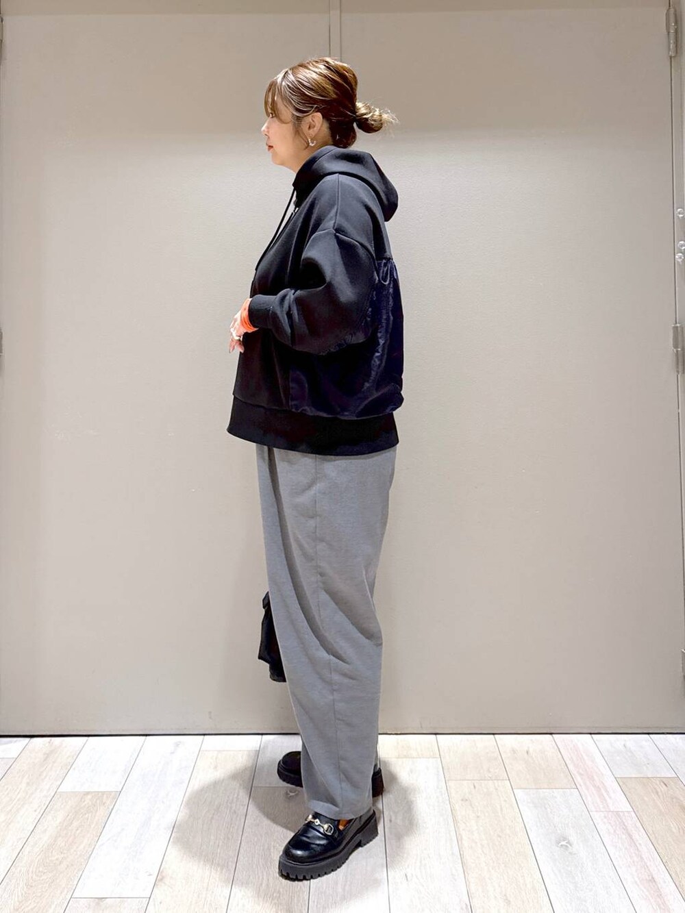 ブラック系のショルダーバッグ、ブラック系のパーカー、オレンジ系のTシャツ/カットソーを着用したレディースの冬コーディネートの4枚目の写真