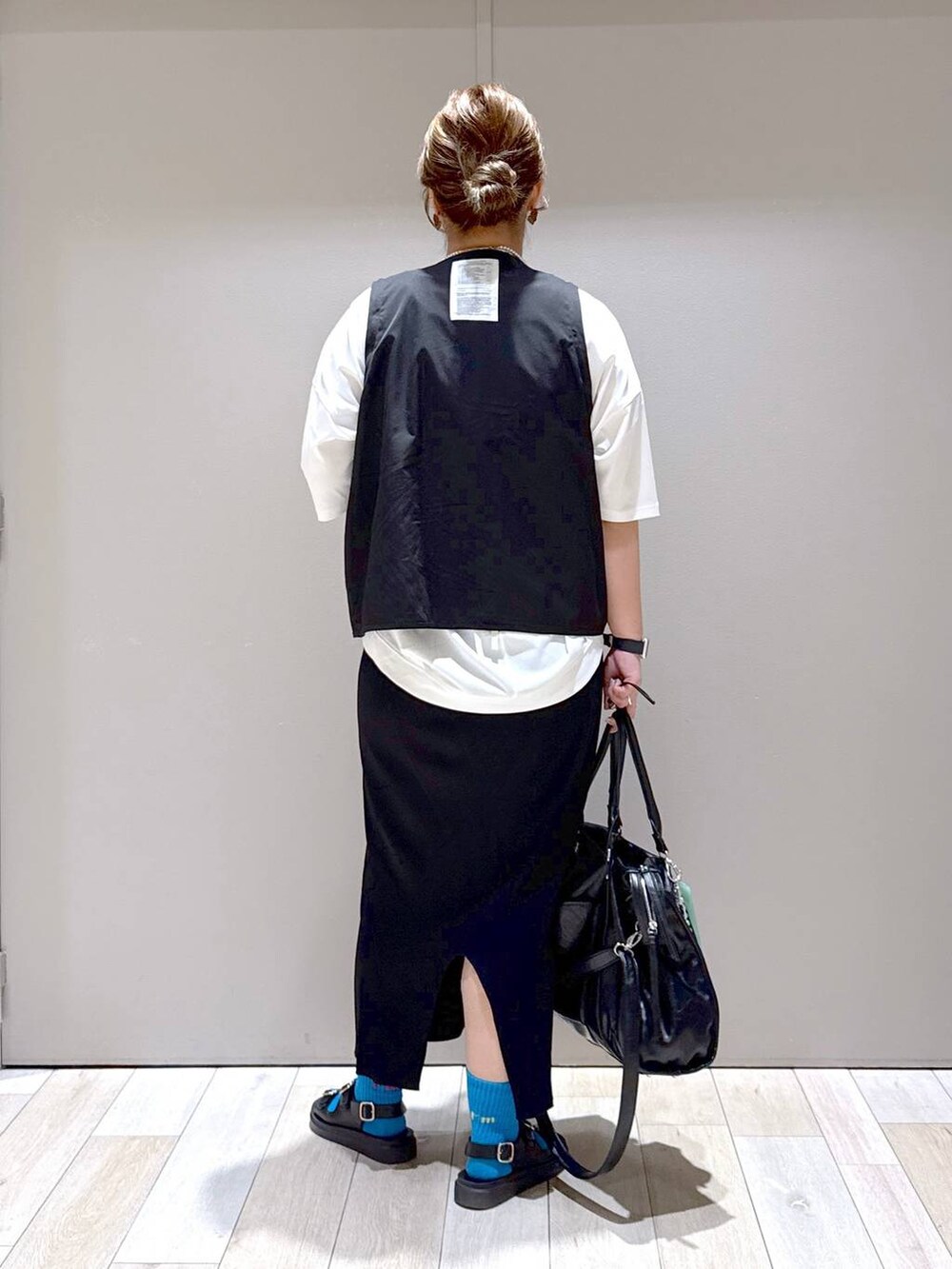 ブラック系のスカート、ブラック系のトートバッグ、ホワイト系のTシャツ/カットソーを着用したレディースの春コーディネートの3枚目の写真