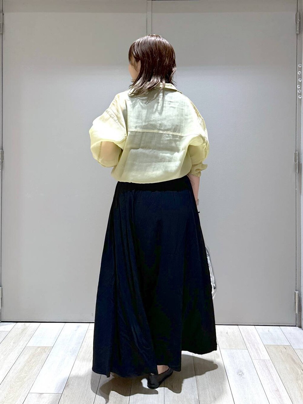 シルバー系のショルダーバッグ、ブラック系のパンプス、ブラック系のスカートを着用したレディースの秋コーディネートの3枚目の写真