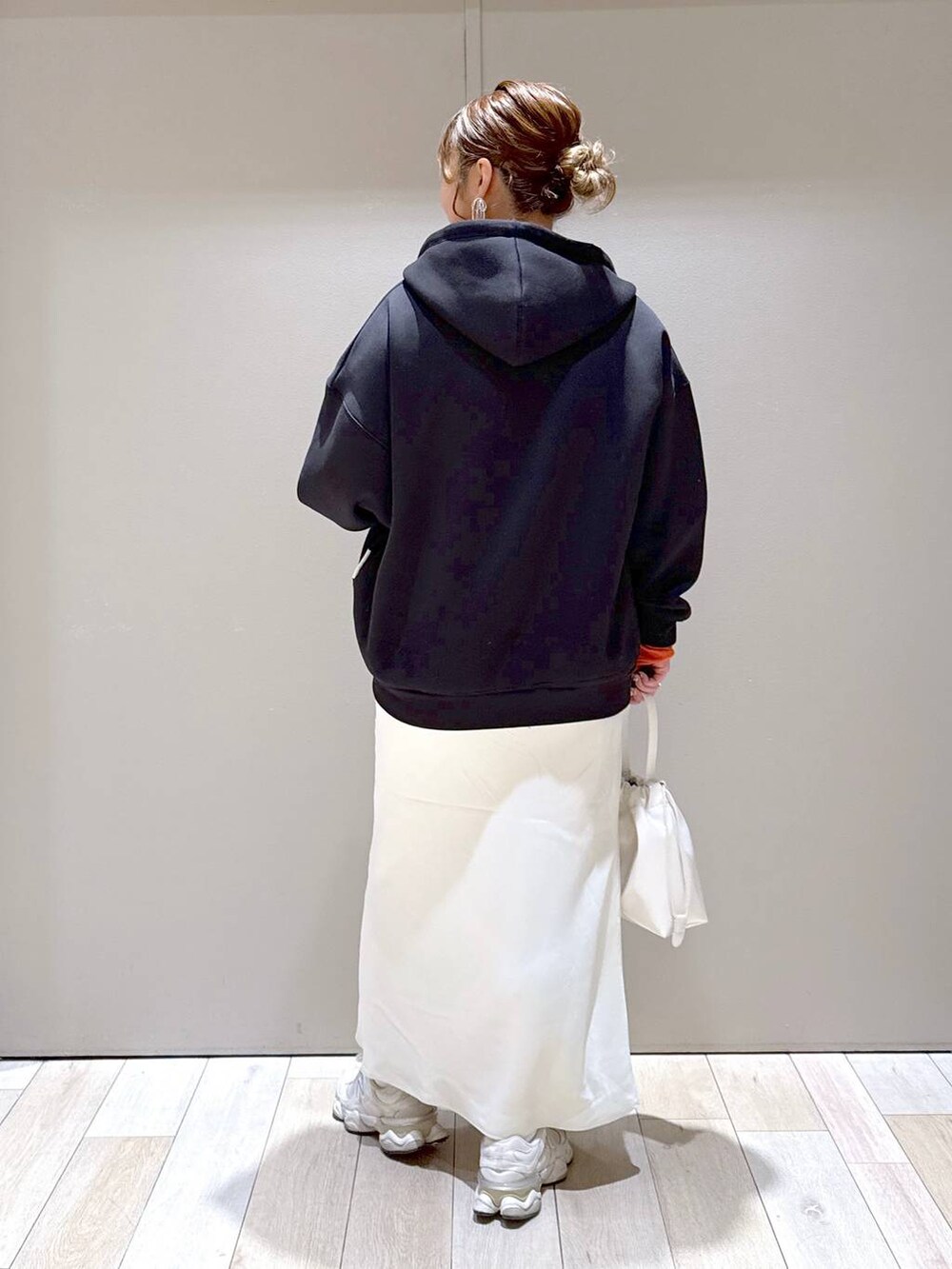 ホワイト系のスカート、ブラック系のパーカー、オレンジ系のTシャツ/カットソーを着用したレディースの冬コーディネートの3枚目の写真