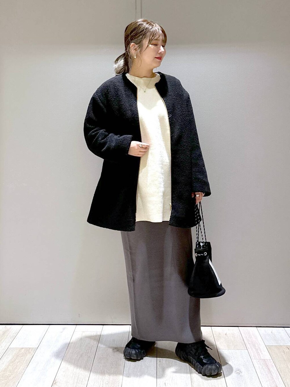 グレー系のスカート、ブラック系のノーカラーコート、ホワイト系のワンピースを着用したレディースの秋コーディネートの4枚目の写真