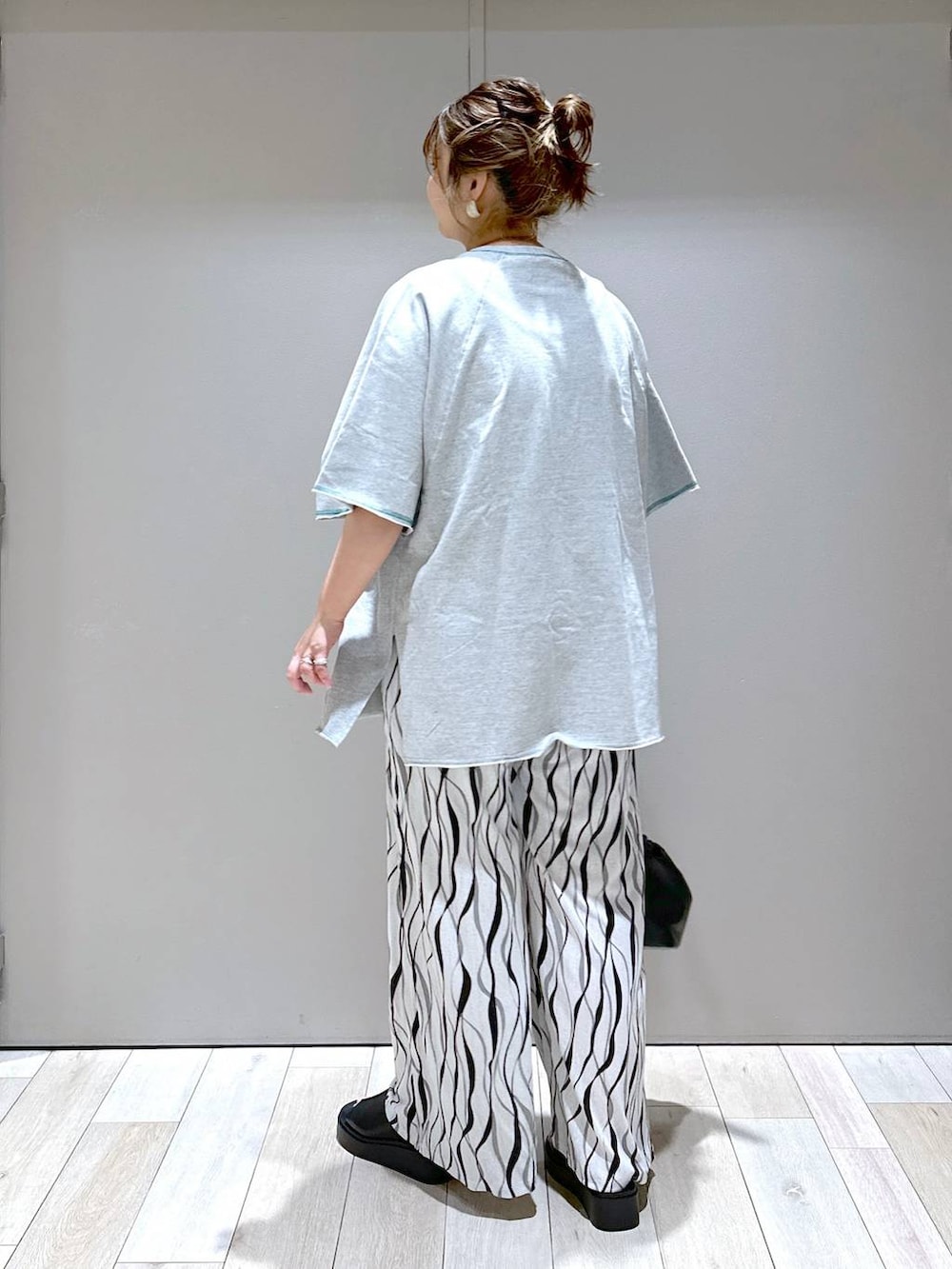 ブラック系のショルダーバッグ、グレー系のTシャツ/カットソー、ブラック系のサンダルを着用したレディースの春コーディネートの3枚目の写真