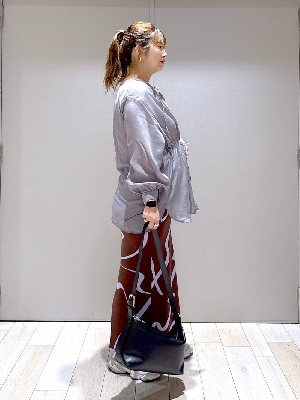 ブラウン系のスカート、ブラック系のショルダーバッグを着用したレディースの夏コーディネートの2枚目の写真