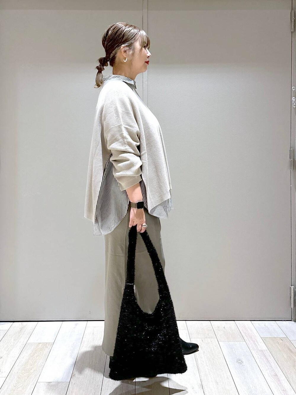 ベージュ系のニット/セーター、ブラック系のシャツ/ブラウス、ブラック系のブーツを着用したレディースの秋コーディネートの2枚目の写真