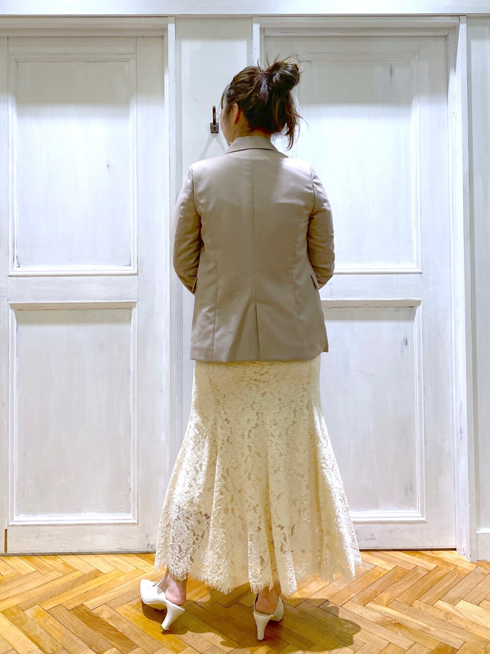 ベージュ系のテーラードジャケット、ホワイト系のスカート、ホワイト系のサンダルを着用したレディースの春コーディネートの3枚目の写真